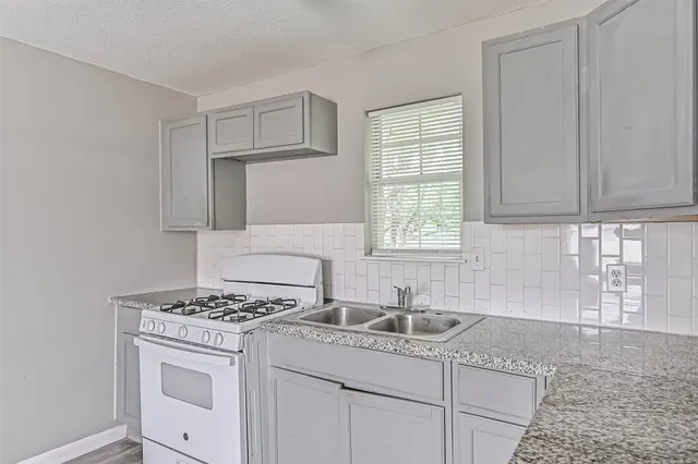 a kitchen with granite countertop a sink stove top oven and cabinets