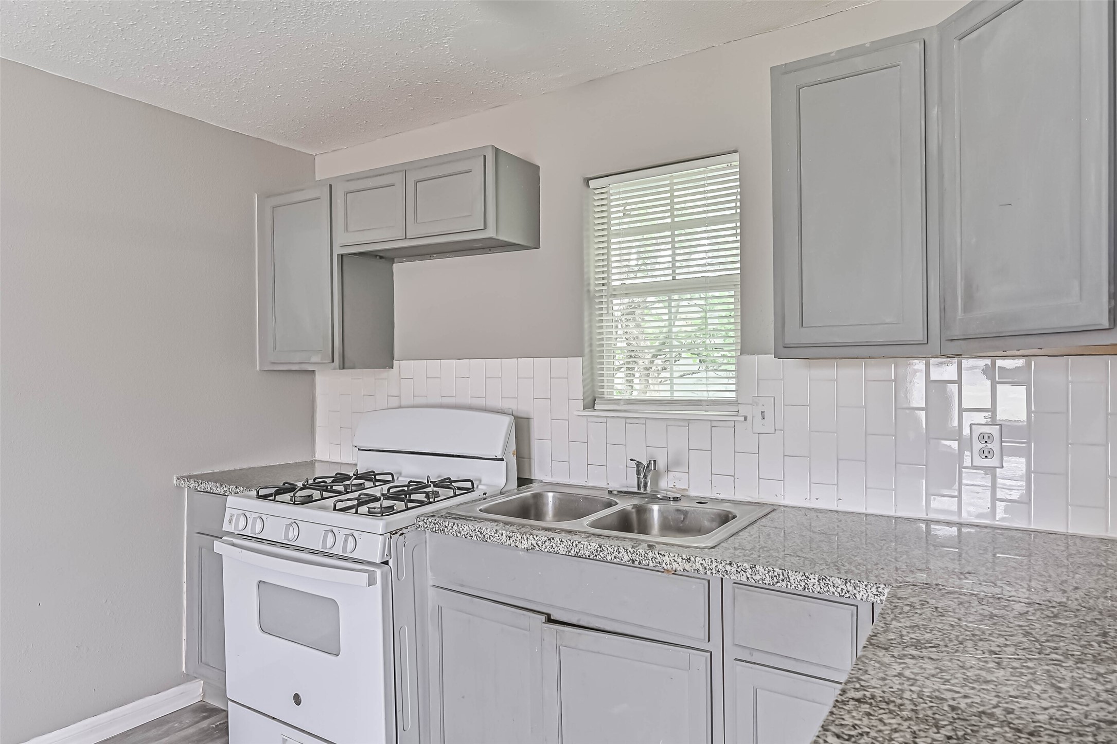 9839 Racine Street, Unit 1/2 Houston, TX 77029 - Photo 14 of 26 a kitchen with granite countertop a sink stove top oven and cabinets