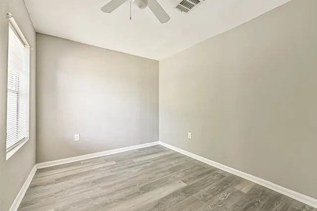 an empty room with wooden floor and windows