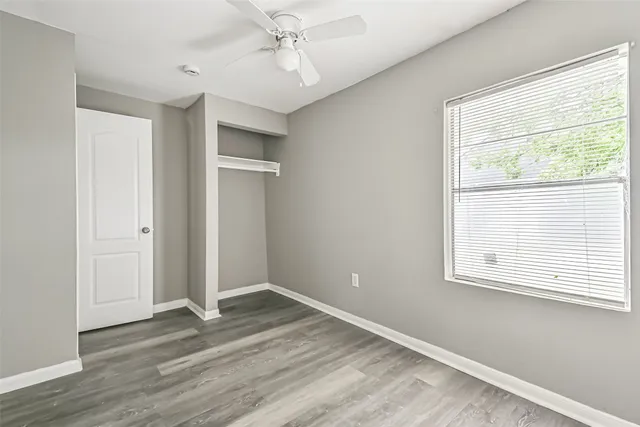 a view of empty room with wooden floor and fan