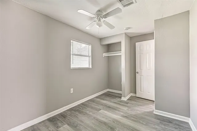 an empty room with windows and ceiling fan