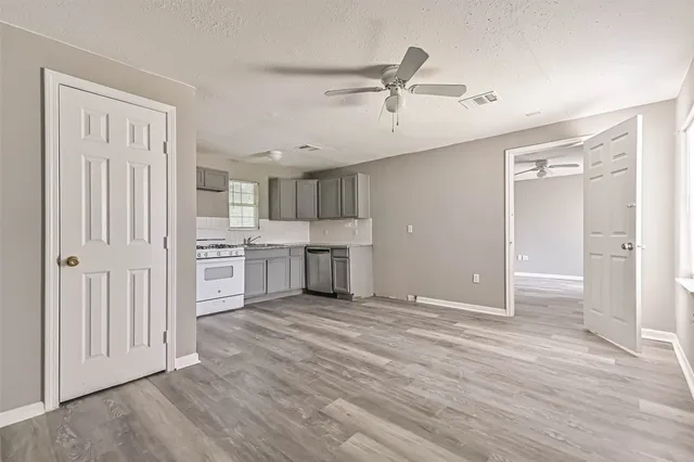 a view of a kitchen with wooden floor electronic appliances and cabinets