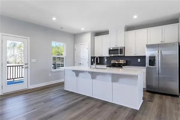 a kitchen with stainless steel appliances granite countertop a stove a sink and white cabinets with wooden floor