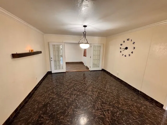 an empty room with chandelier fan and windows