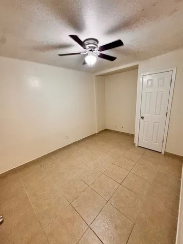 an empty room with a ceiling fan and carpet