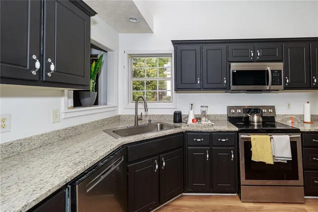 a kitchen with granite countertop a sink stainless steel appliances and cabinets
