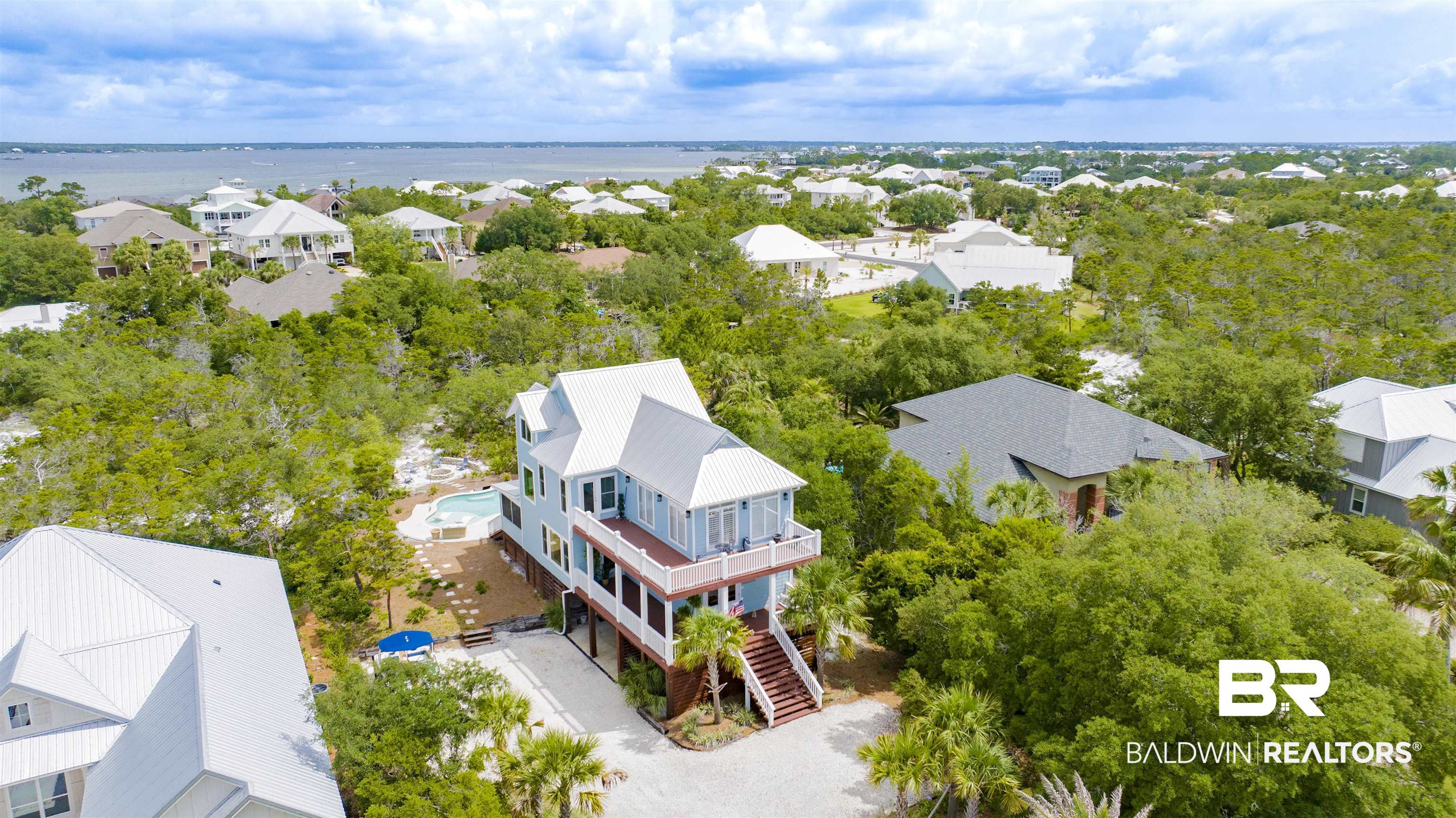 30351 River Road Orange Beach, AL 36561 - Photo 34 of 44 Elevated coastal residence featuring multiple levels of outdoor decking, a private swimming pool, and a gravel driveway