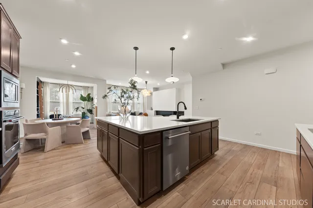 a large kitchen with stainless steel appliances a large counter top a sink dishwasher and a fireplace with wooden floor