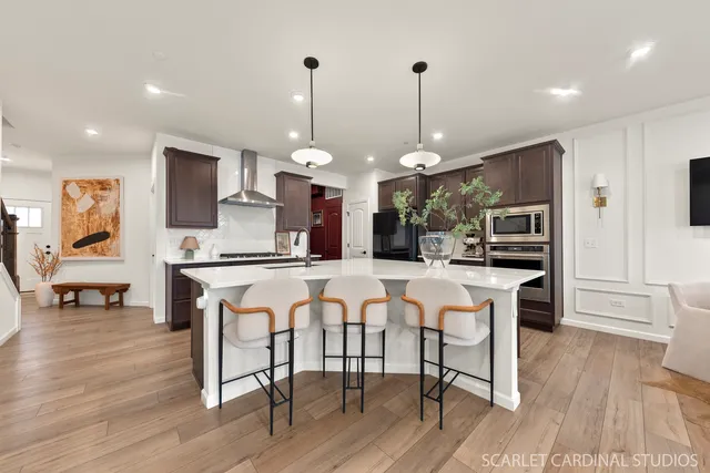 a kitchen with stainless steel appliances kitchen island granite countertop a table chairs and a wooden floor