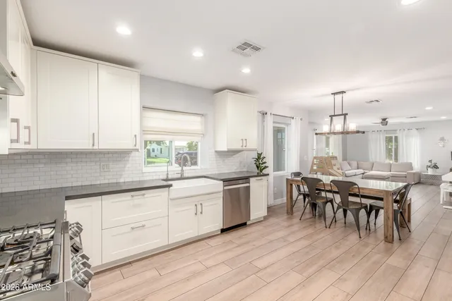 a kitchen with lots of white furniture a sink a dining table and chairs