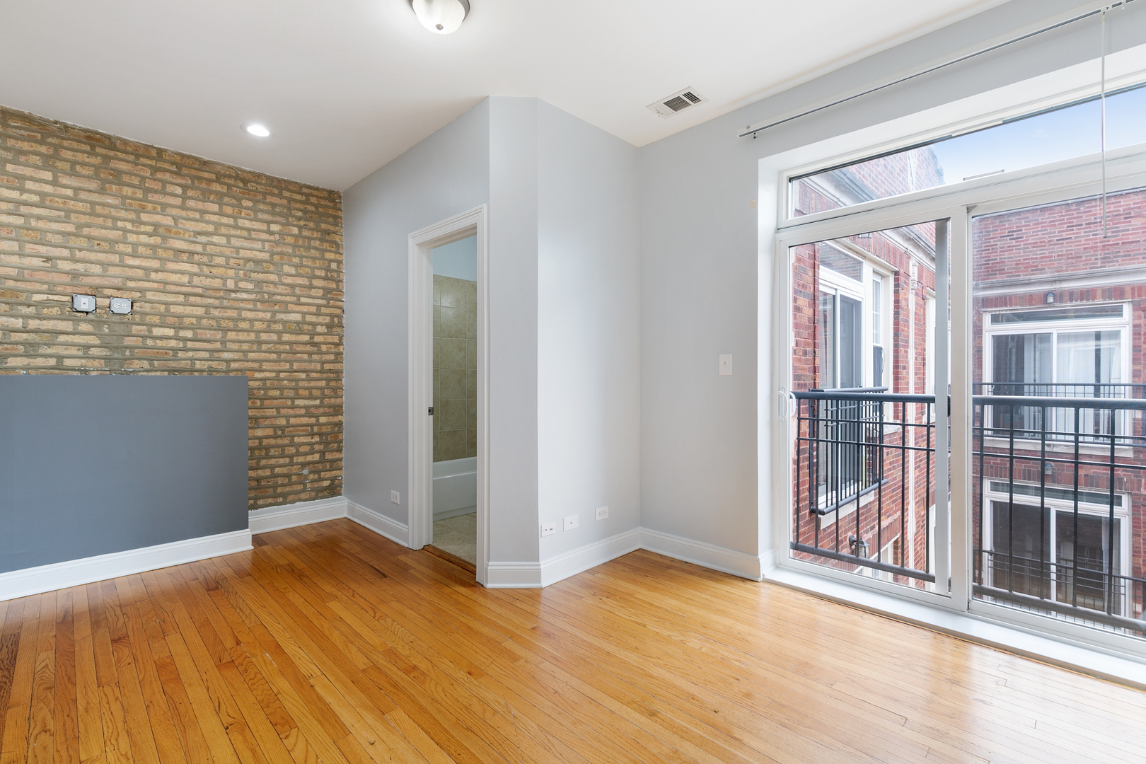 2007 West Jarvis Avenue, Unit 3 Chicago, IL 60645 - Photo 2 of 18 a view of an empty room with wooden floor and a window