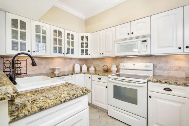 a kitchen with granite countertop white cabinets and white appliances