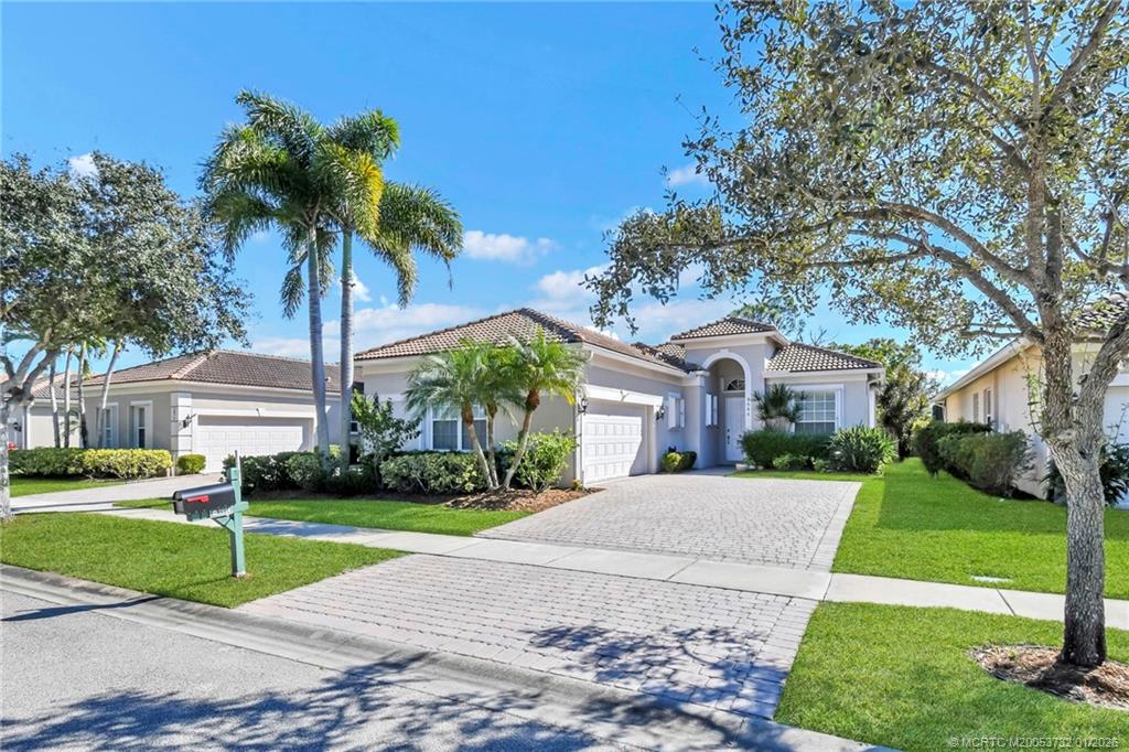 a front view of a house with a yard and palm trees
