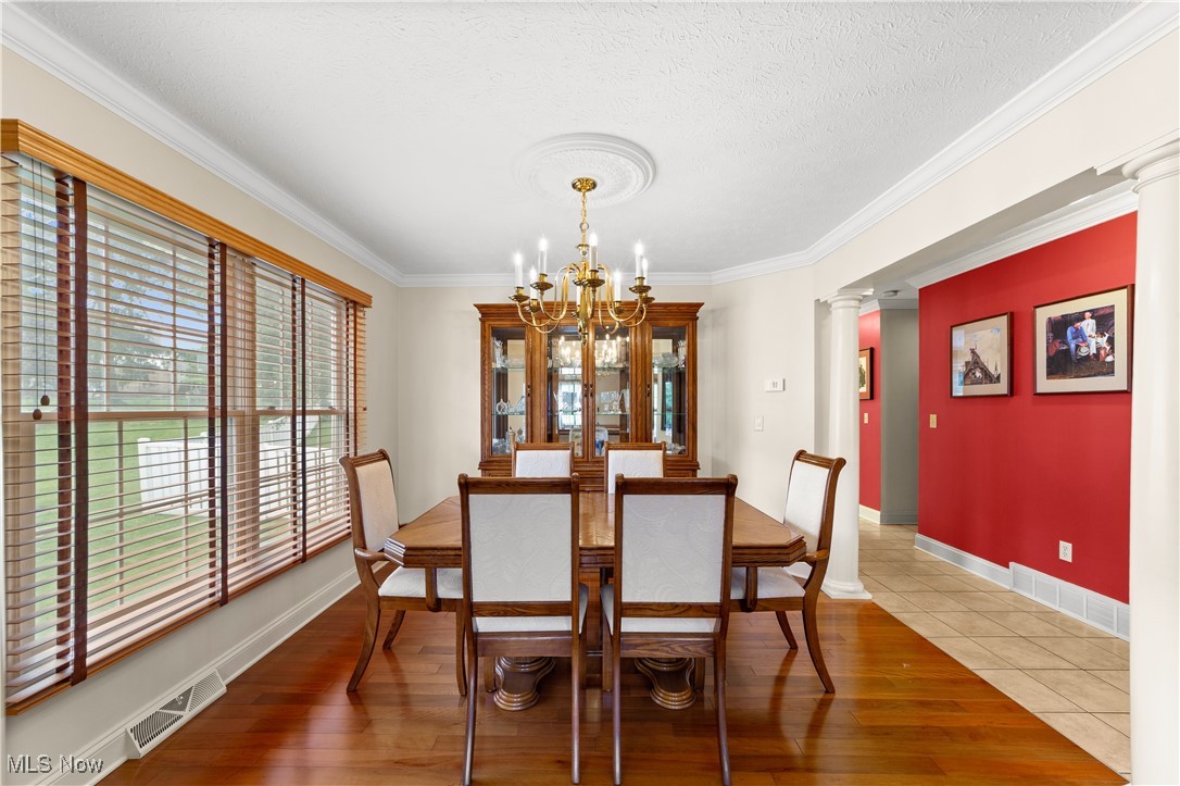 4500 Brooks Road Cleveland, OH 44105 - Photo 8 of 50 Dining area featuring wood finished floors, a chandelier, decorative columns, ornamental molding, and a textured ceiling