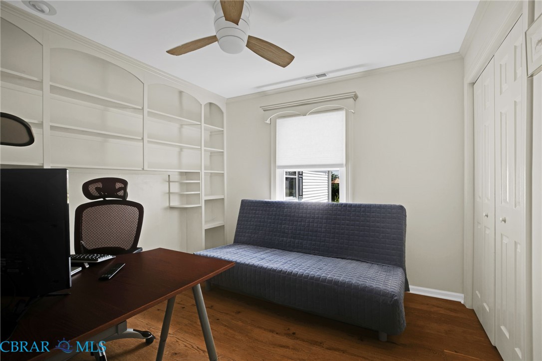 9093 Stump Point Road Hayes, VA 23072 - Photo 21 of 40 Room featuring extensive built-in shelving, wood-finish flooring, a ceiling fan, a window with roller shade, and bi-fold closet doors