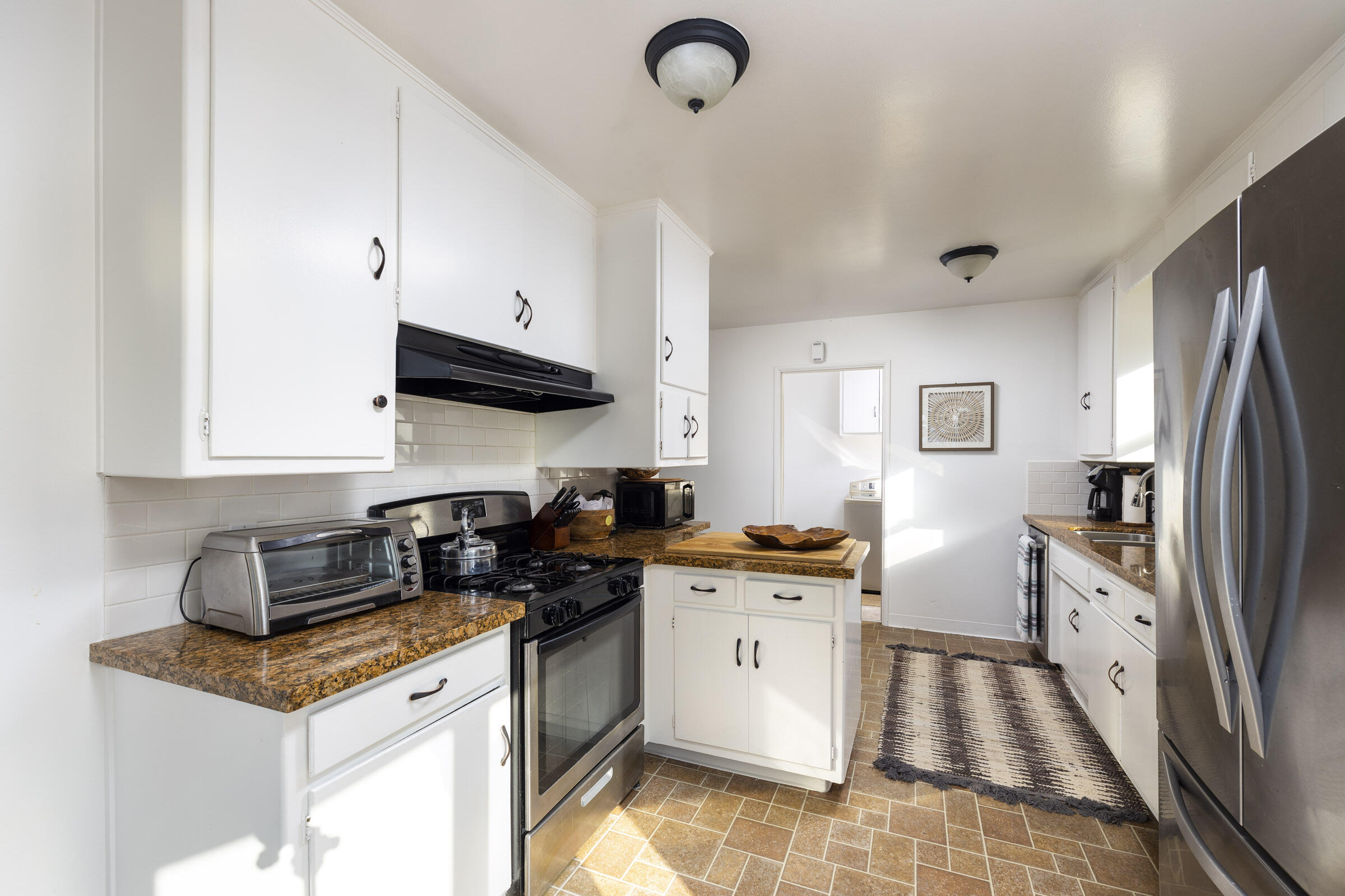 1919 El Camino De La Luz Santa Barbara, CA 93109 - Photo 17 of 28 a kitchen with granite countertop a sink a stove top oven a refrigerator a counter top space and cabinets