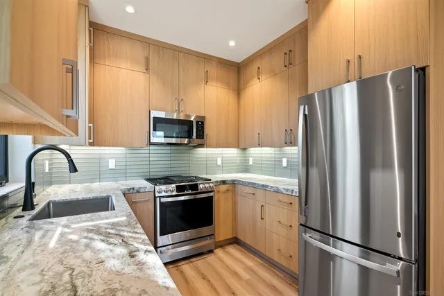 a kitchen with stainless steel appliances granite countertop a refrigerator sink and stove
