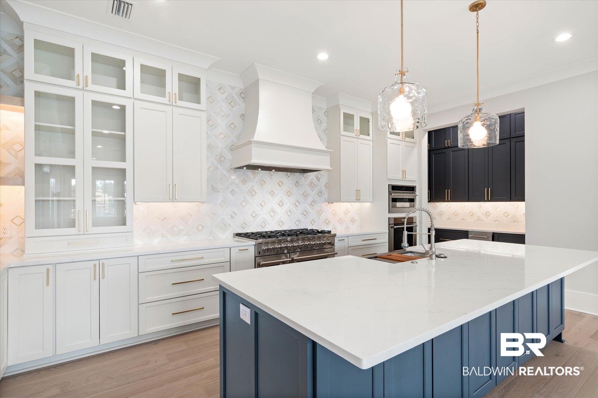 853 Inlet Circle Gulf Shores, AL 36542 - Photo 13 of 55 Kitchen with light wood-style floors, an island with sink, stainless steel appliances, visible vents, and custom exhaust hood