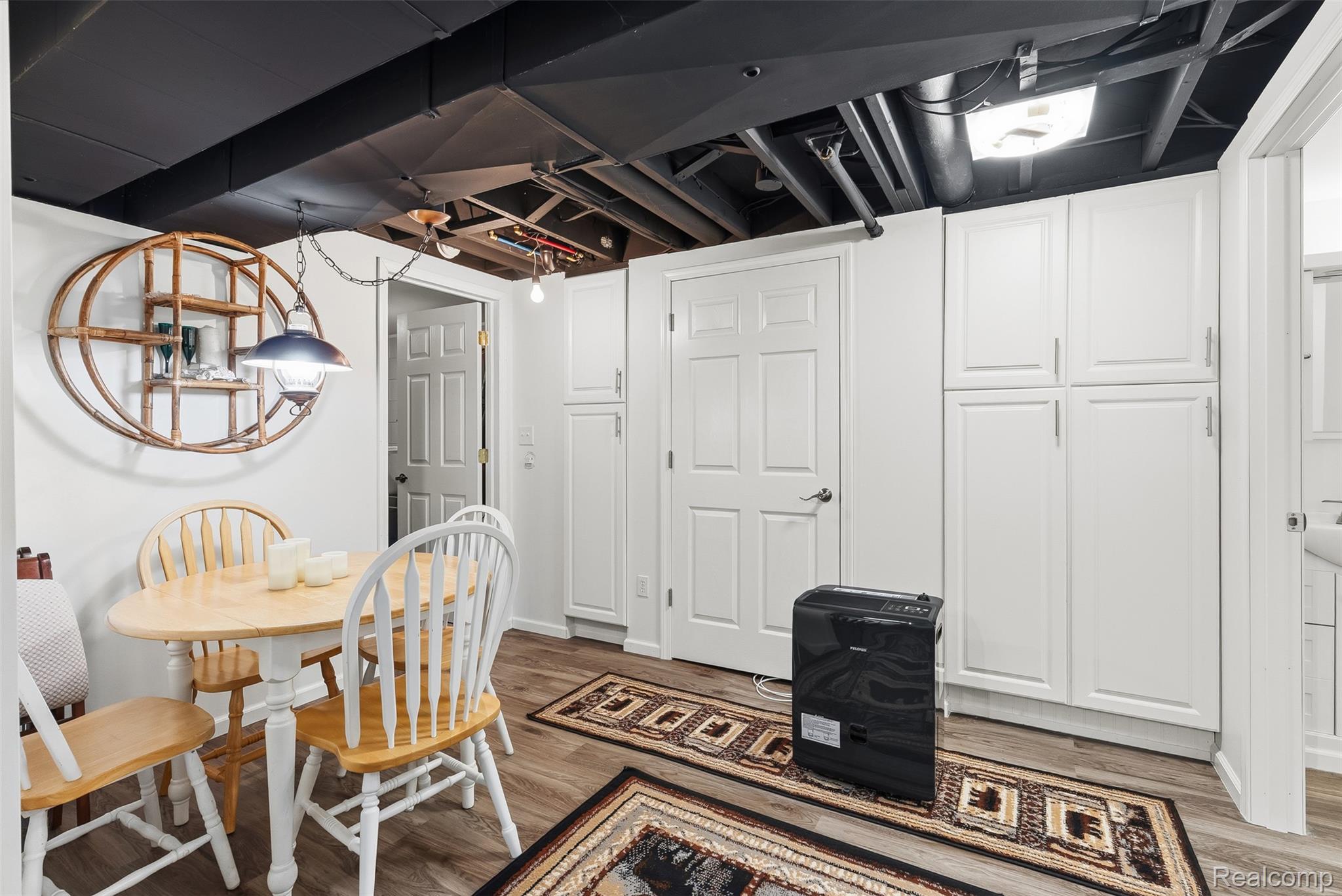 2227 North Graf Road Caro, MI 48723 - Photo 36 of 51 White paneled cabinetry, wood-finish flooring, and a painted exposed ceiling with surface-mounted lighting