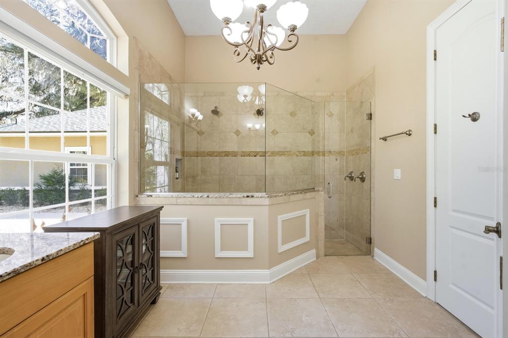 6595 Collier Road St. Augustine, FL 32092 - Photo 29 of 98 a bathroom with a granite countertop sink a large mirror and a bathtub next to a window
