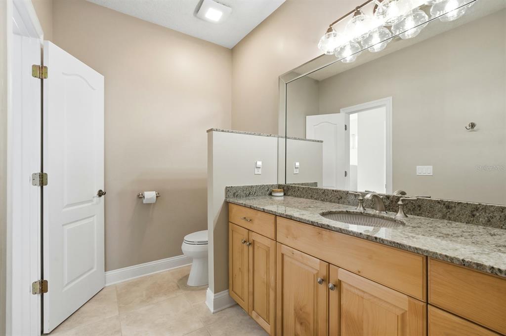 6595 Collier Road St. Augustine, FL 32092 - Photo 56 of 98 a bathroom with a granite countertop sink a toilet and a mirror
