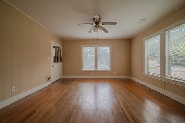 a view of an empty room with wooden floor and a window