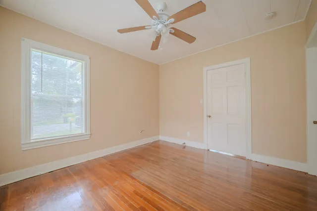 an empty room with wooden floor and windows