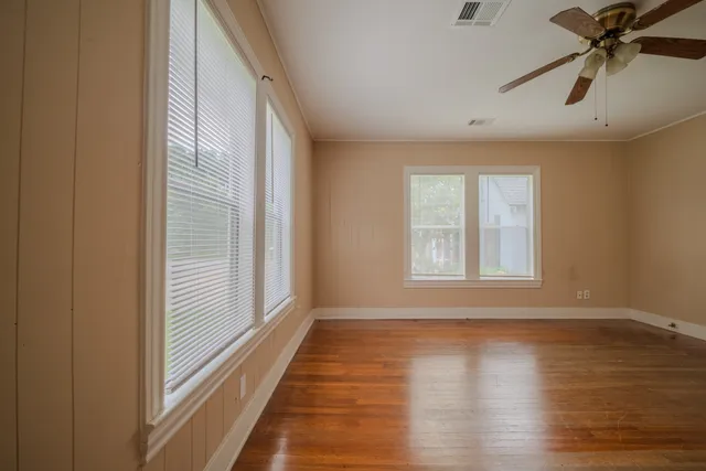 a view of an empty room with wooden floor and a window