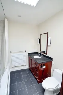 a bathroom with a granite countertop toilet a sink and a mirror