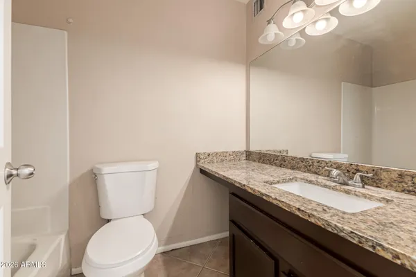 a bathroom with a granite countertop toilet sink and mirror