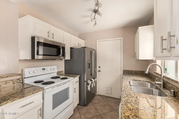 a kitchen with stainless steel appliances granite countertop a sink stove a refrigerator and a microwave