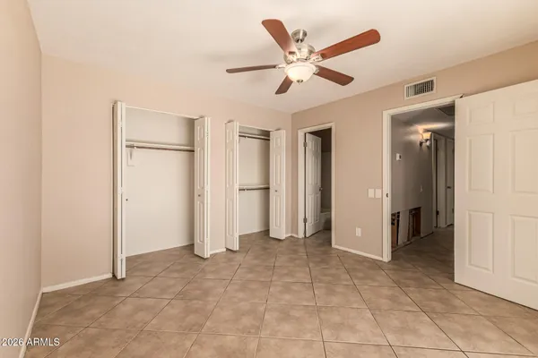 an empty room with closet and a ceiling fan