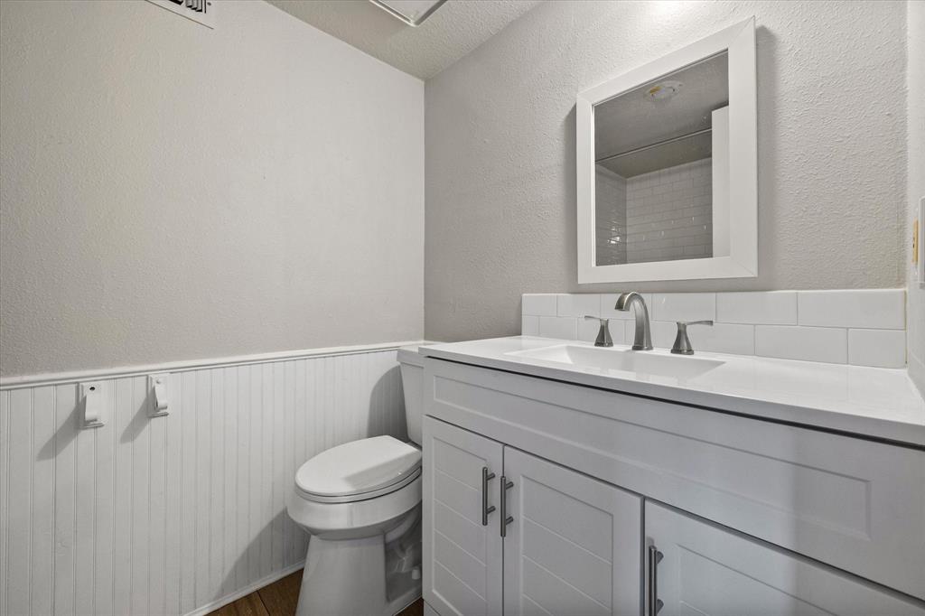 443 County Road 3799 Springtown, TX 76082 - Photo 25 of 33 Full bathroom with a wainscoted wall, vanity, a textured wall, dark wood-style floors, and a shower