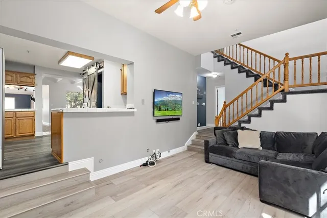 a living room with couches and a dining table with wooden floor