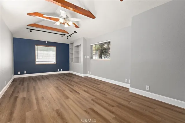 a view of empty room with wooden floor and fan
