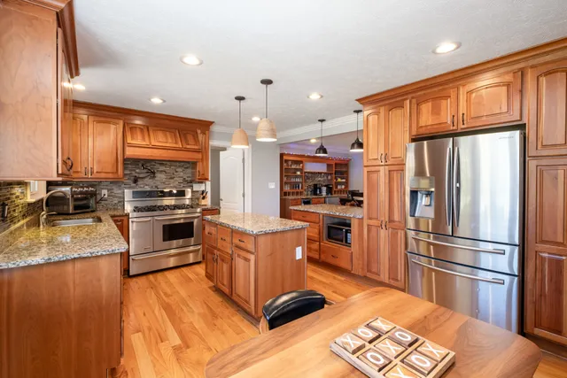 a kitchen with stainless steel appliances granite countertop a refrigerator a stove top oven a sink dishwasher and white cabinets with wooden floor