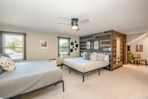 a bedroom with two beds and large windows