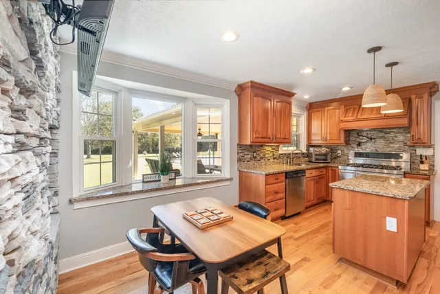 a kitchen with stainless steel appliances granite countertop a stove a sink dishwasher and a refrigerator with wooden floor