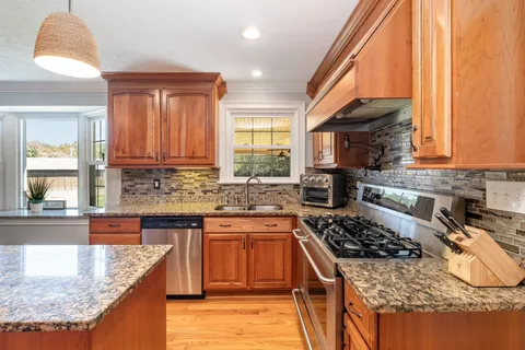 a kitchen with stainless steel appliances granite countertop a stove a sink and a microwave