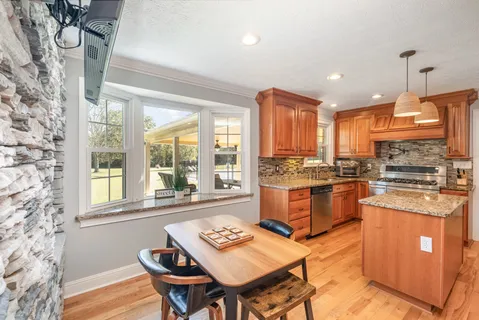 a kitchen with stainless steel appliances granite countertop a stove a sink dishwasher and a refrigerator with wooden floor