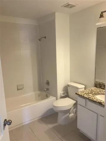 a bathroom with a granite countertop bathtub shower sink vanity and toilet