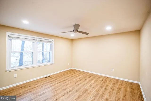 a view of empty room with wooden floor and a window