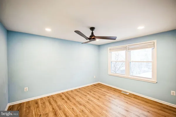 a view of empty room with wooden floor and fan
