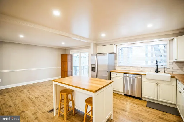 a kitchen with stainless steel appliances a sink a stove a refrigerator and white cabinets