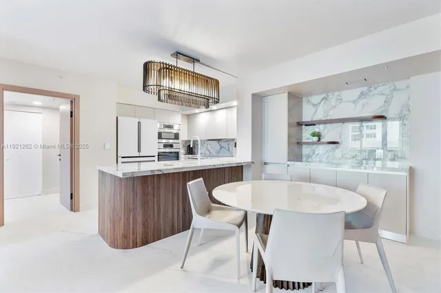 a kitchen with a dining table chairs and refrigerator