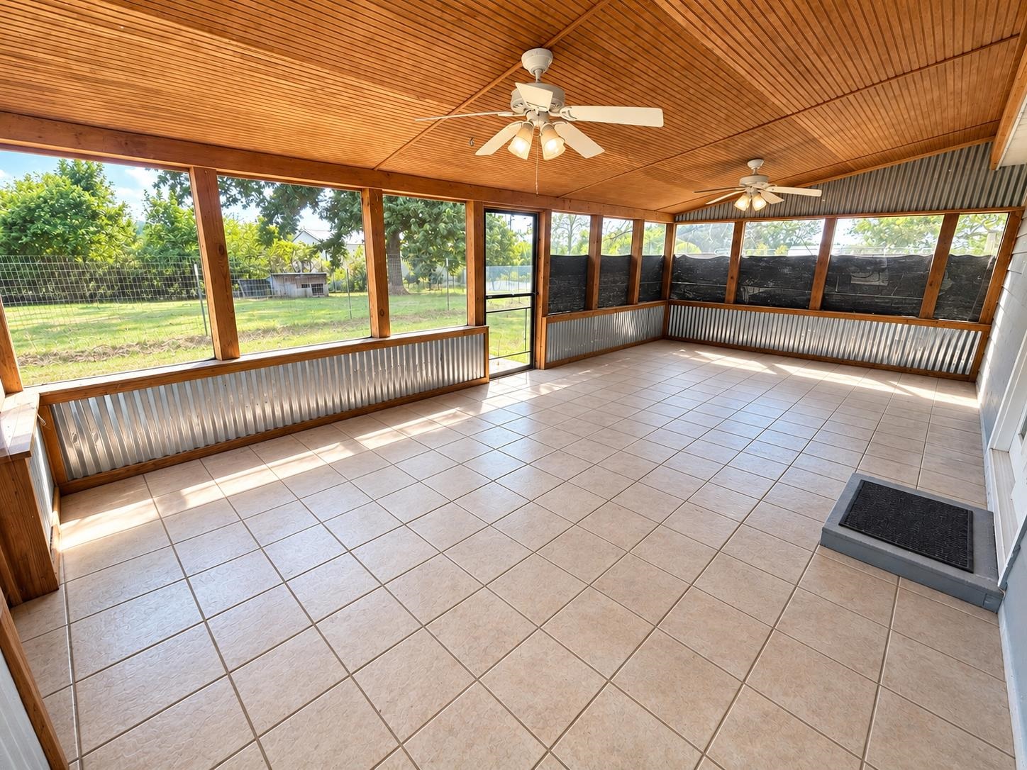 3771 West Union Road Millington, TN 38053 - Photo 14 of 16 Expansive screened porch featuring a wood-finish tongue-and-groove ceiling, dual ceiling fans, tile flooring, and corrugated metal wainscoting