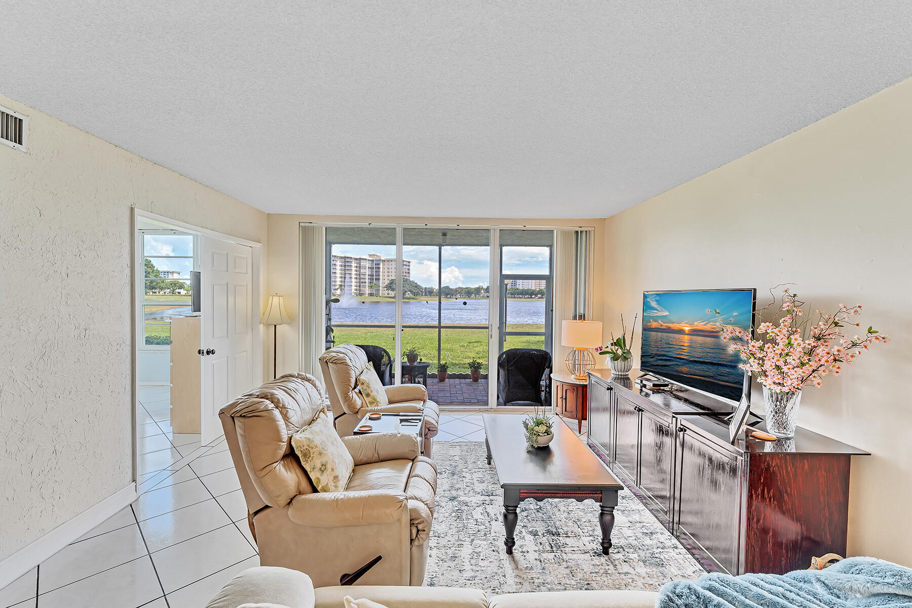 3091 North Course Drive, Unit 108 Pompano Beach, FL 33069 - Photo 23 of 42 a living room with furniture a flat screen tv and a floor to ceiling window