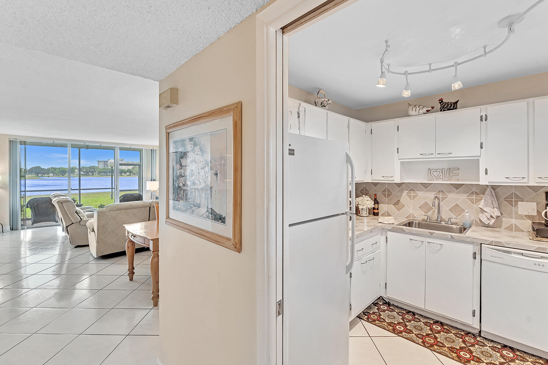 3091 North Course Drive, Unit 108 Pompano Beach, FL 33069 - Photo 6 of 42 a kitchen with a refrigerator a sink and white cabinets