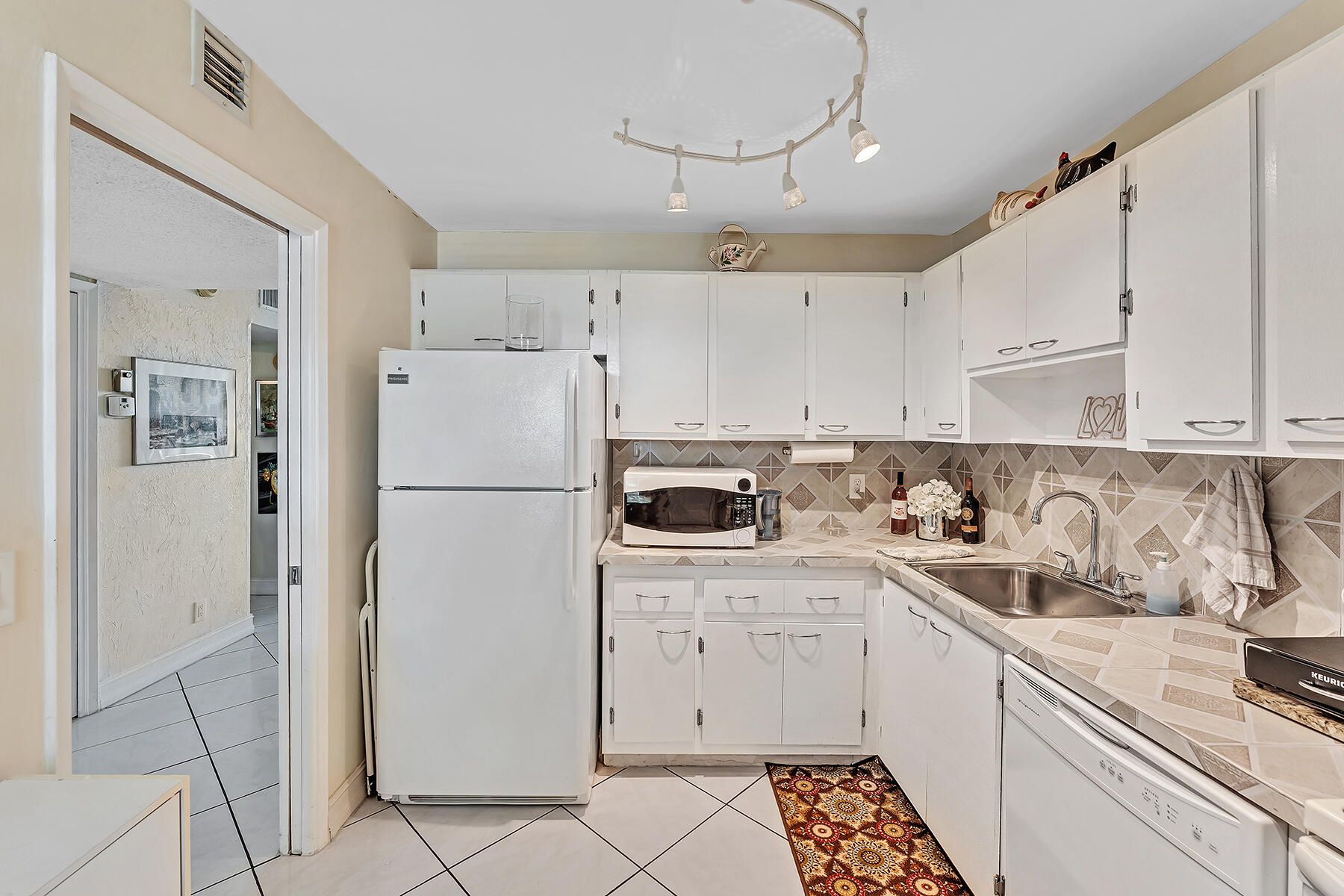 3091 North Course Drive, Unit 108 Pompano Beach, FL 33069 - Photo 9 of 42 a kitchen with a refrigerator sink and cabinets