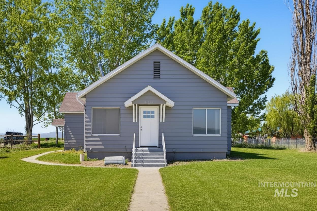30013 Apple Valley Road Parma, ID 83660 - Photo 2 of 25 Front facade featuring a pitched roof, light gray siding, and a white entry door with glass panels. AI enhanced